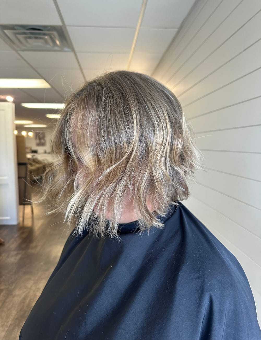 Short wavy blonde bob hairstyle in a salon setting.